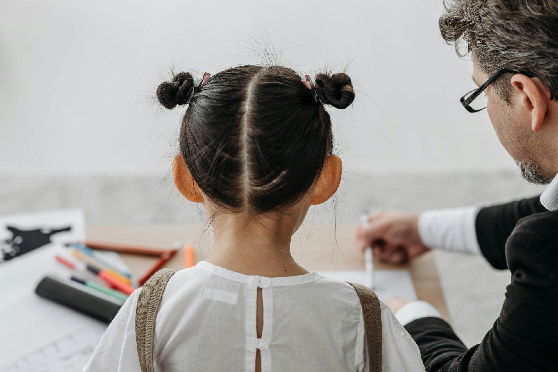 A child sitting next to a social worker at a desk, viewed from behind.